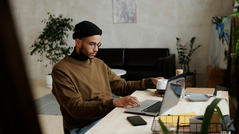 Ein Mann sitzt an einem Arbeitstisch vor einem Laptop.